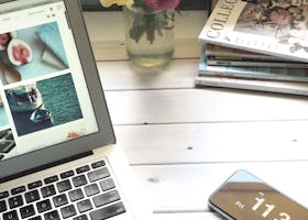 Elegant workspace featuring a laptop, smartphone, and fresh roses in a bright setting.